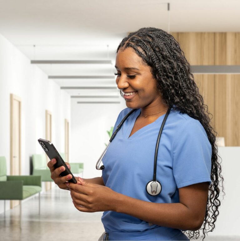 female healthcare worker in a hospital lobby smiling and looking at her phone
