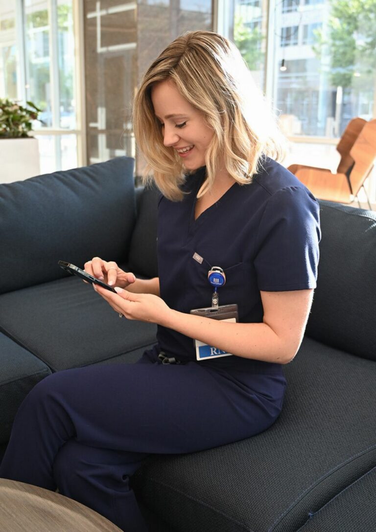 Woman in scrubs looking at phone smiling