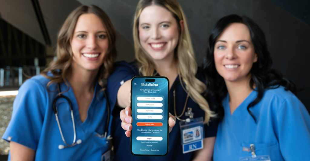 Three female nurses smiling and holing phone to camera displaying the StaffDNA mobile app sign-up page.