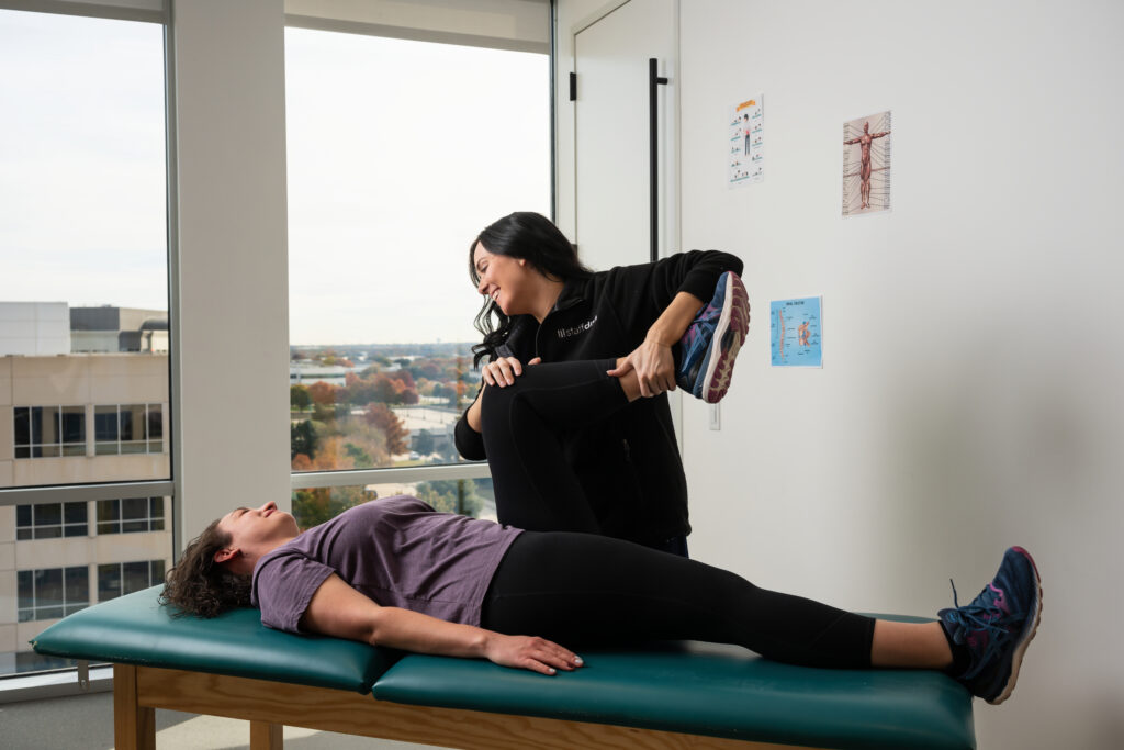 Female physical therapist assisting patient with a stretch