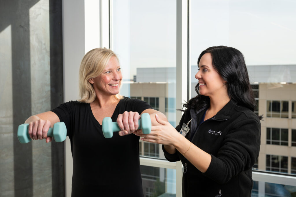 Female therapist helping woman lift weights