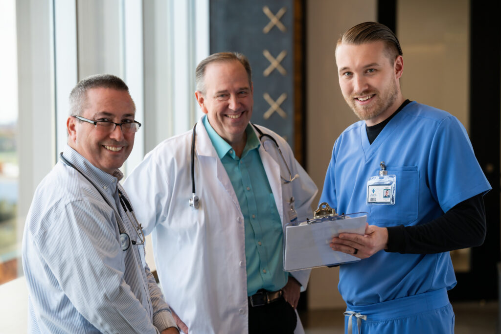 Two male doctors and a nurse comparing notes in an office