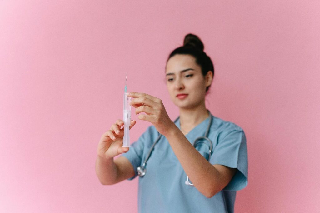 Female nurse out of focus holding an injector that is in focus