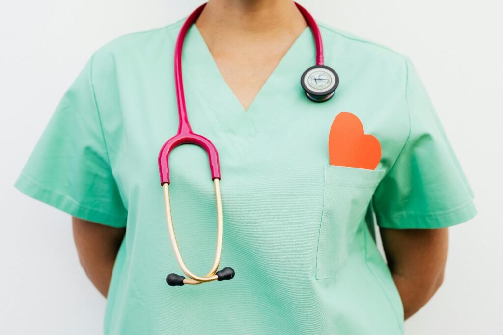 Nurse in scrubs with a paper heart on chest