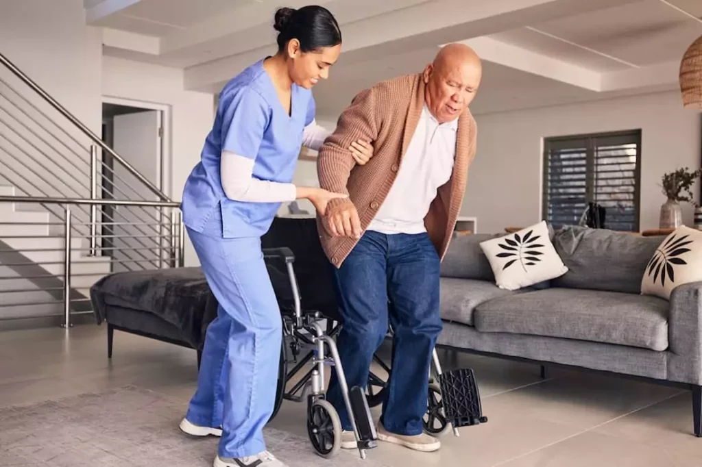 Occupational therapist helping elderly patient into wheelchair