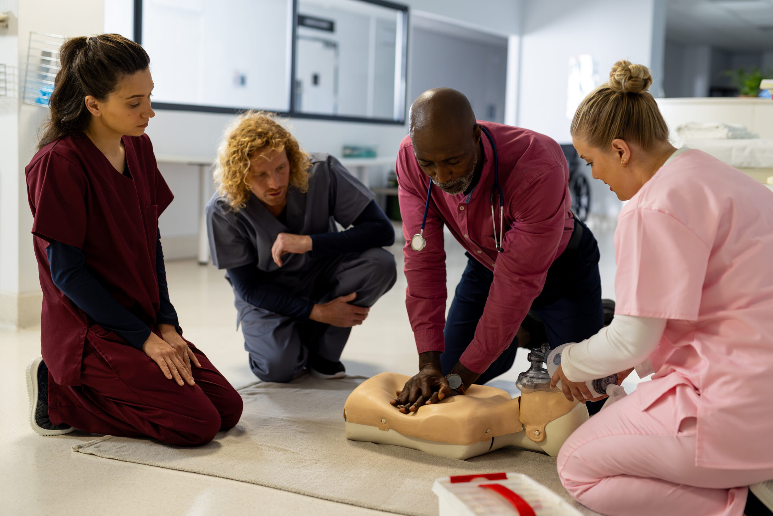 Nurse performing CPR on training dummy in front of other training nurses