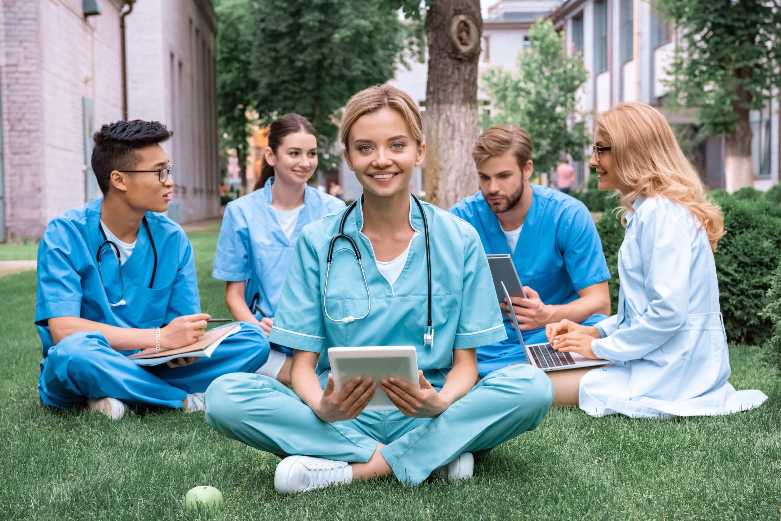 A group of five nurses studying outside