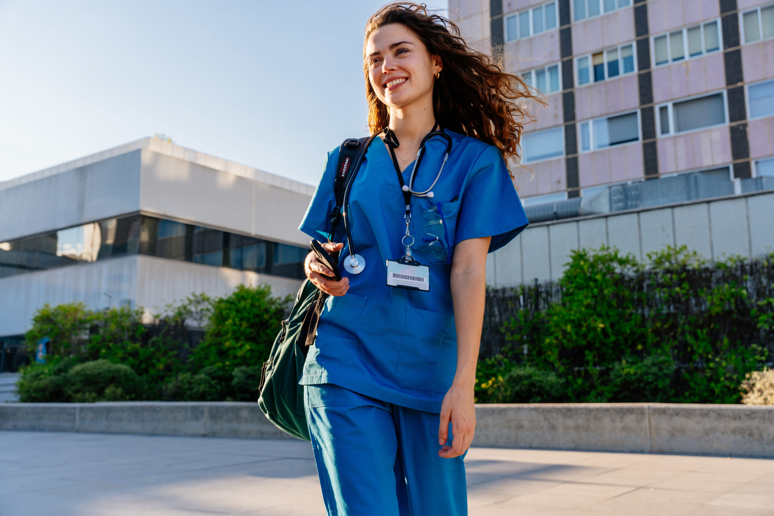 Female nurse walking with hair billowing in the wind.