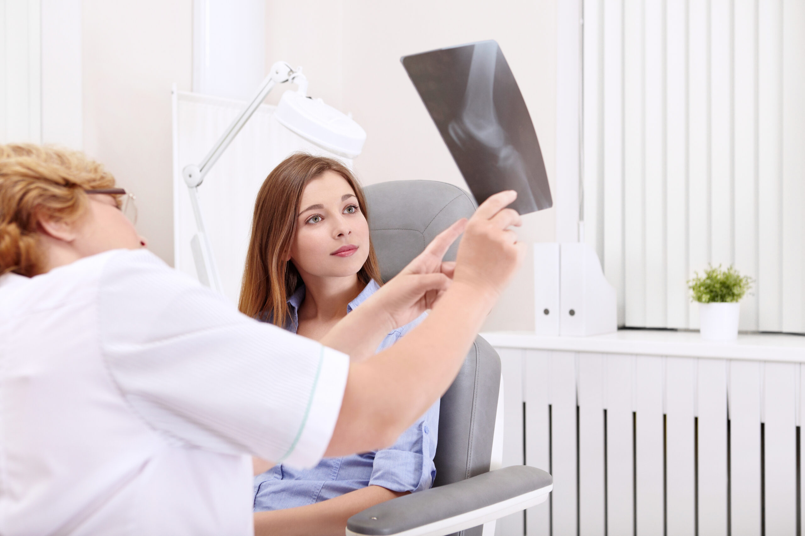 An X-Ray Tech showing woman a picture of her leg xray and explaining her findings